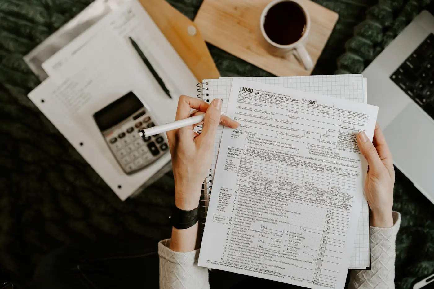 Tax forms, a calculator and a cup of coffee spread across a desk