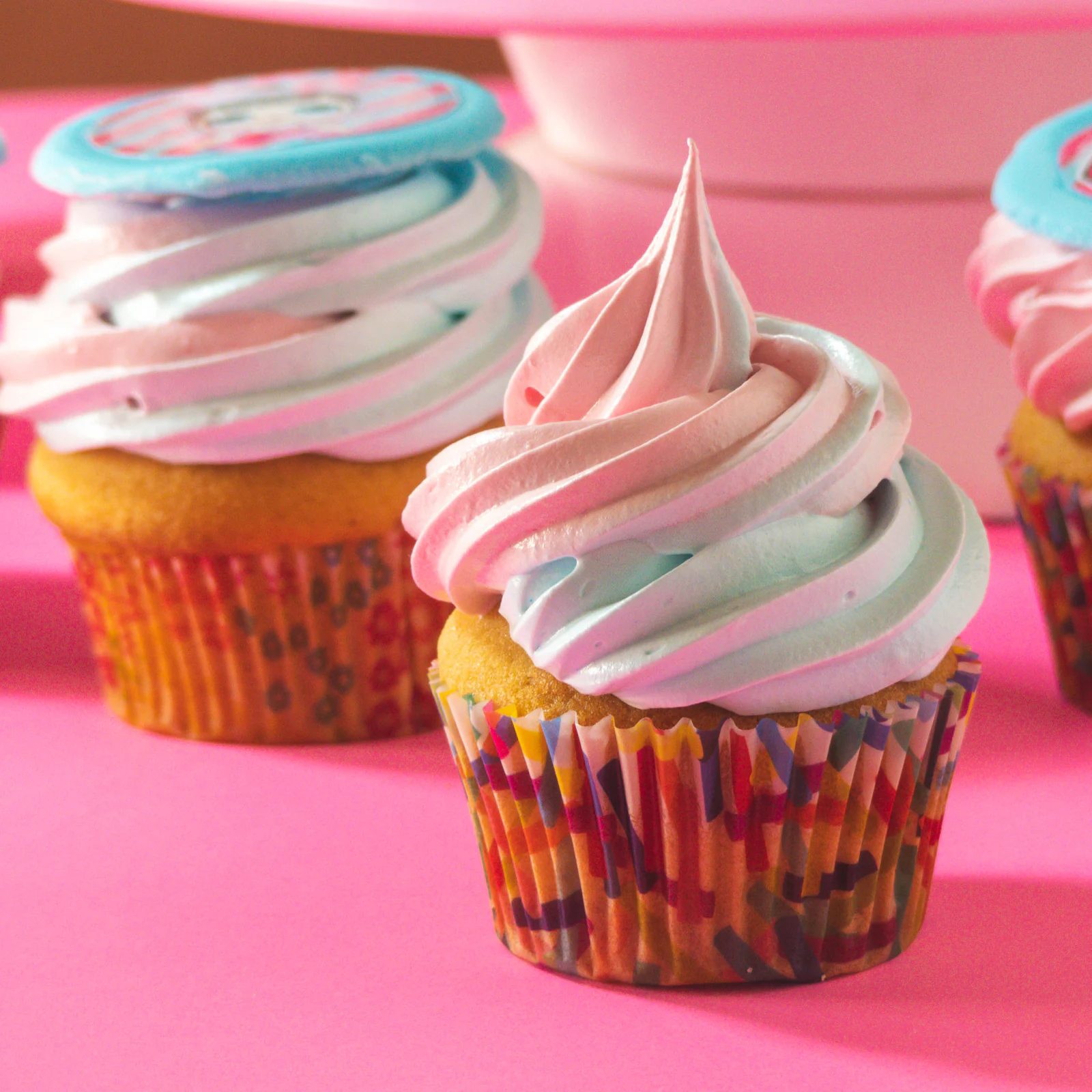 Pink and white swirled frosting cupcake on a pink background