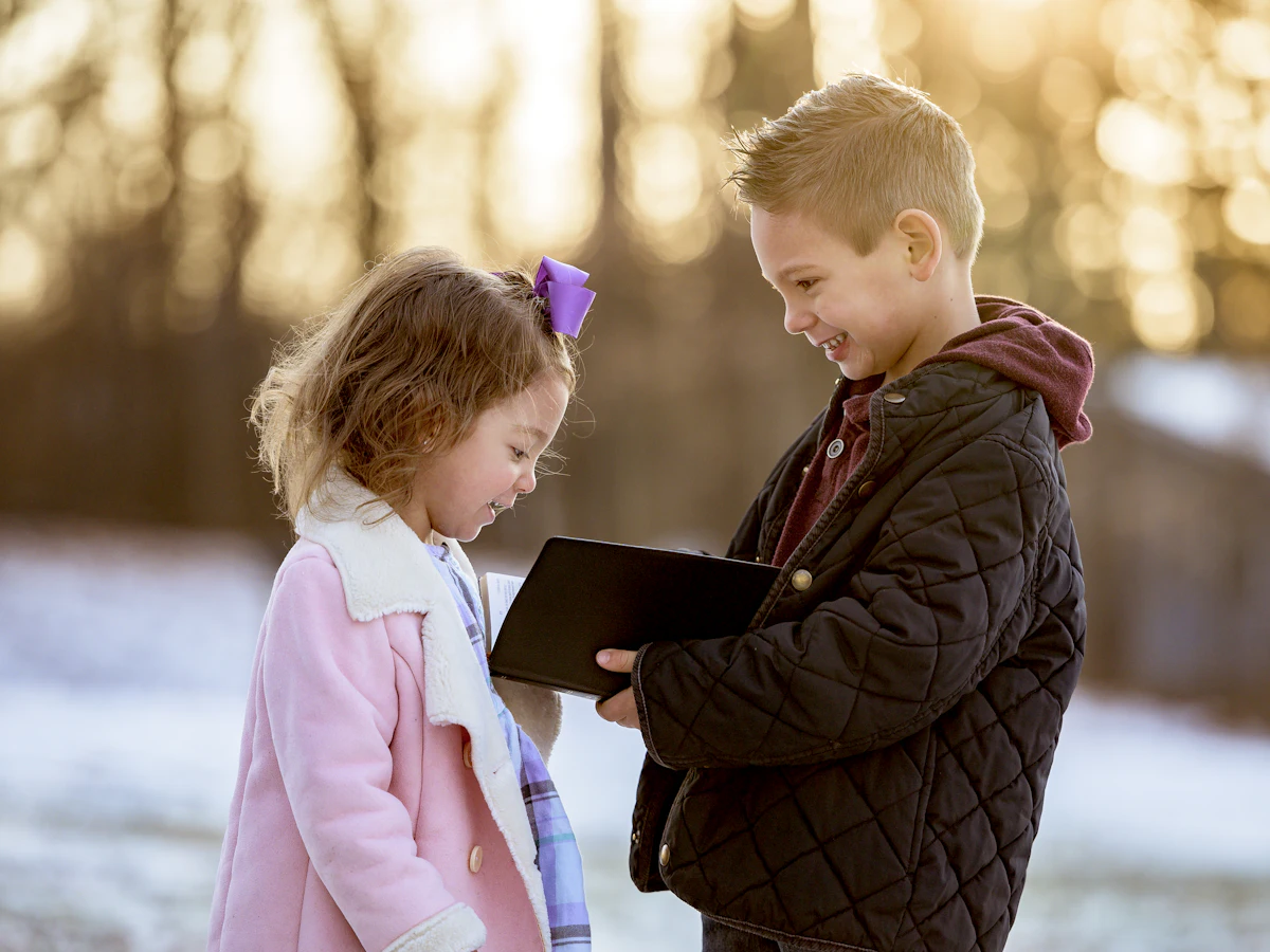 Two children reading a Bible together outdoors