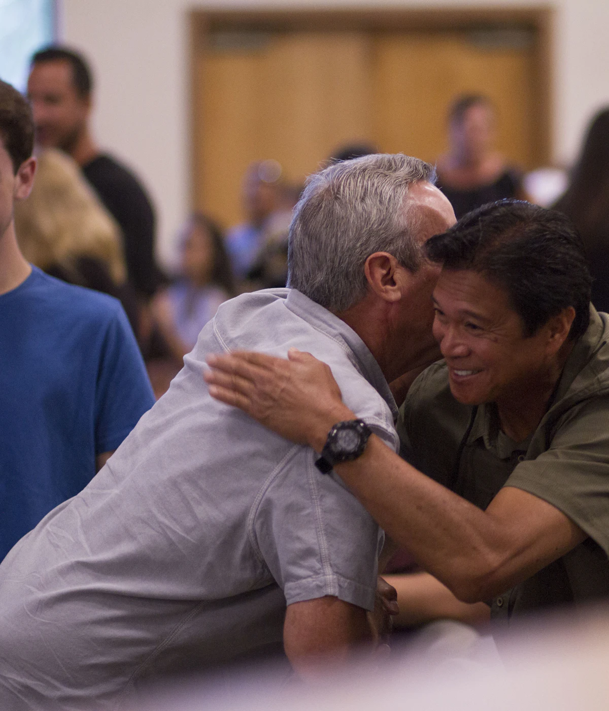 Two men embracing warmly in a church lobby
