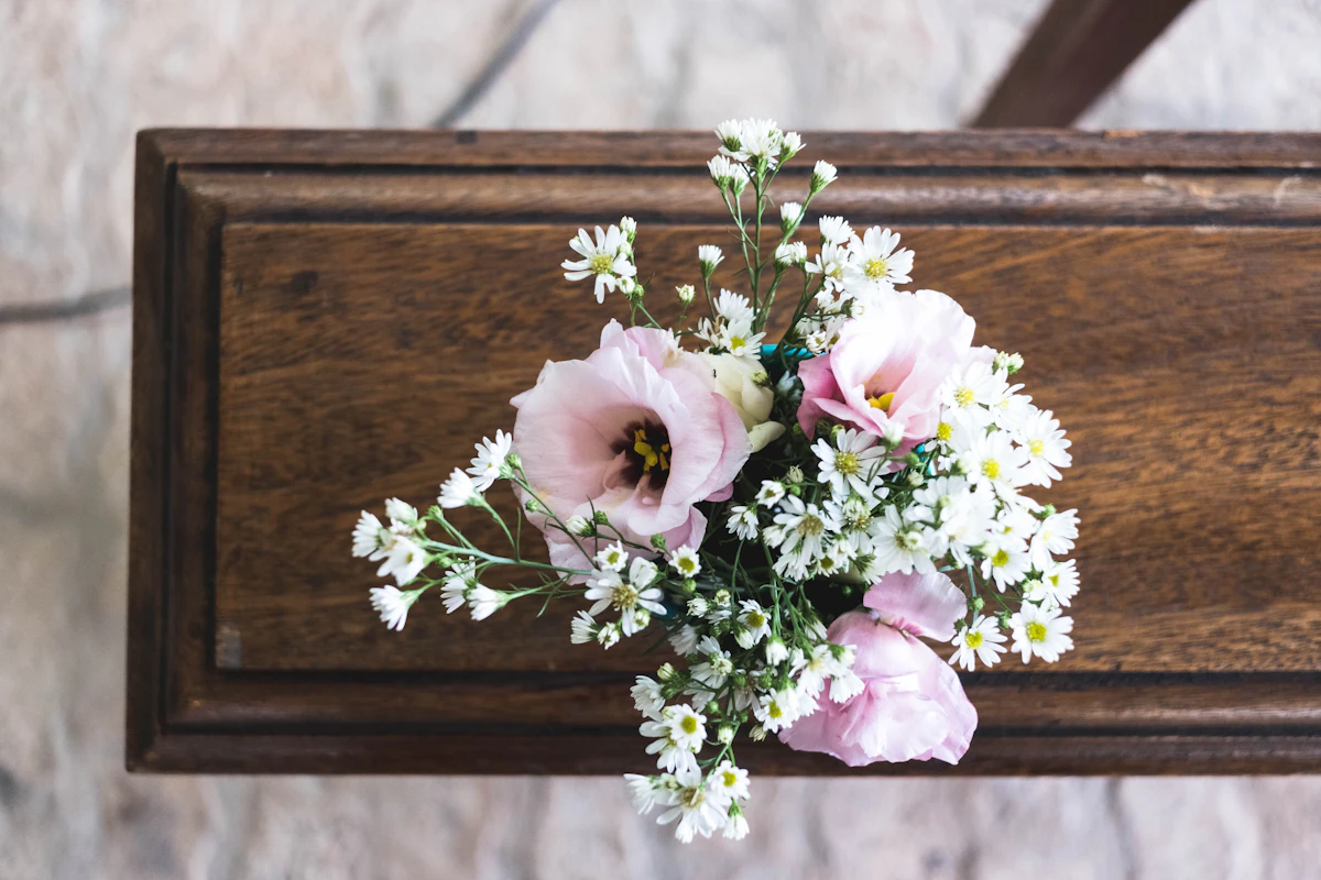 Delicate pink and white flowers resting on a wooden casket