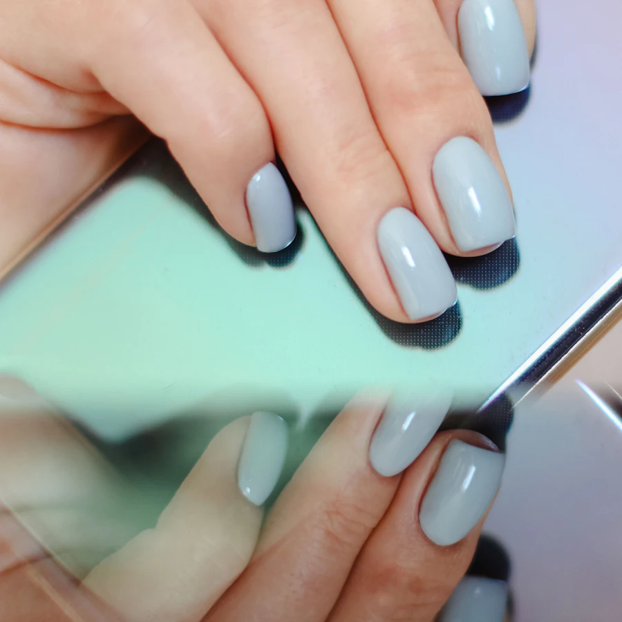 Pale blue gel nails reflected in a mirror