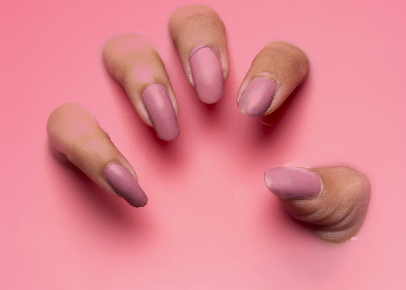 Freshly manicured hands against a soft pink background