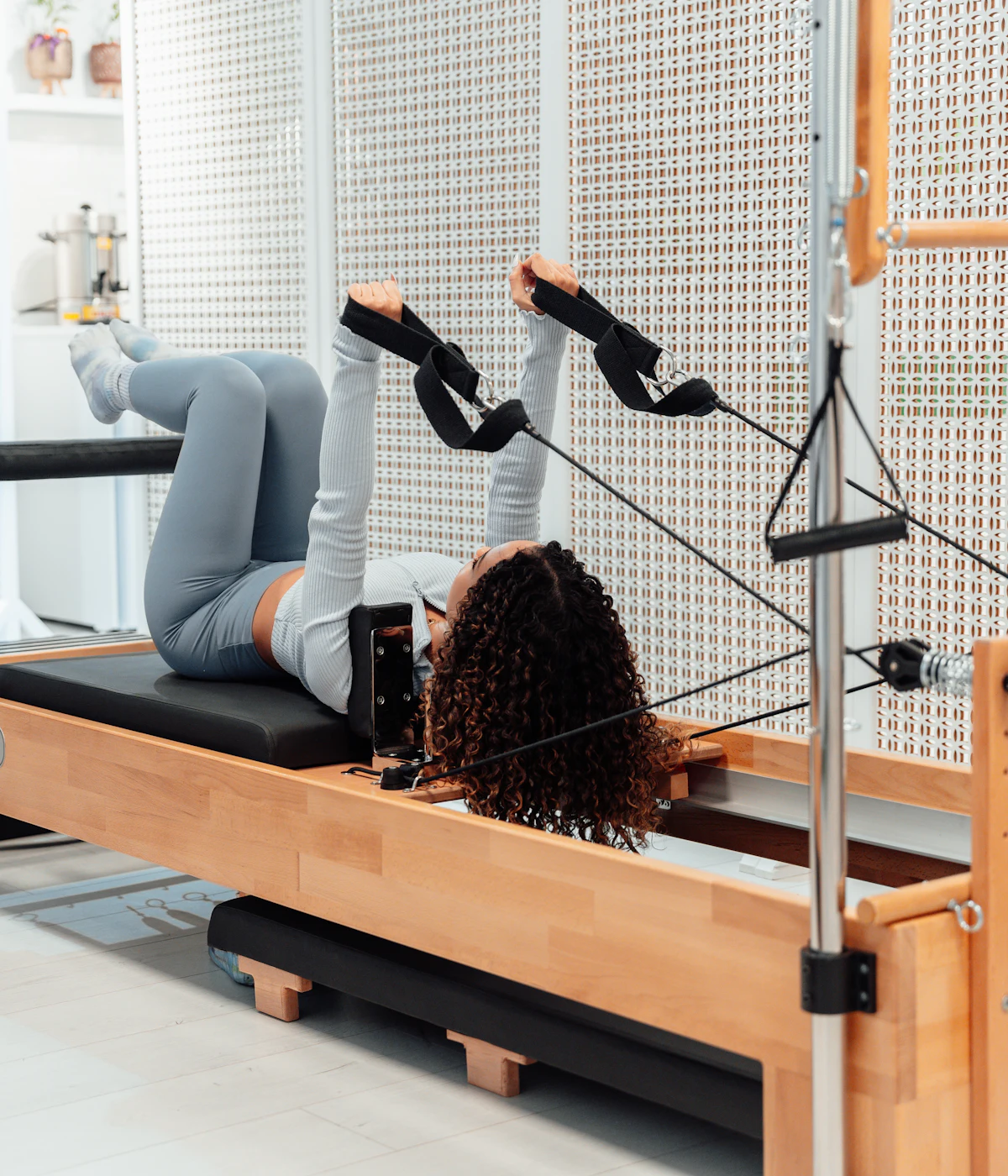 Student working with springs on a wooden Pilates tower